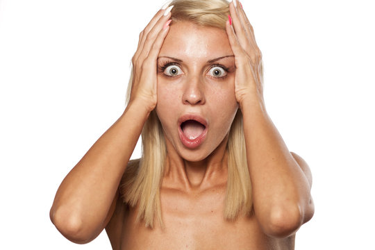 Shocked young woman without makeup posing in the studio