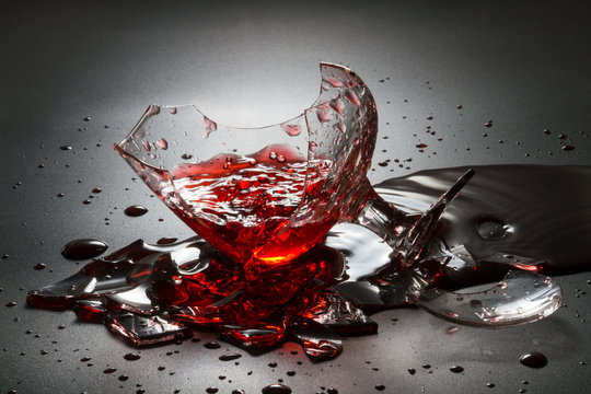 Pouring red wine on broken glass.