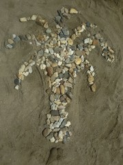 Palm tree made of small rocks in the sand on the beach