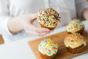 close up of woman with glazed cupcakes or muffins