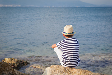 child in hat looking at sea and ship