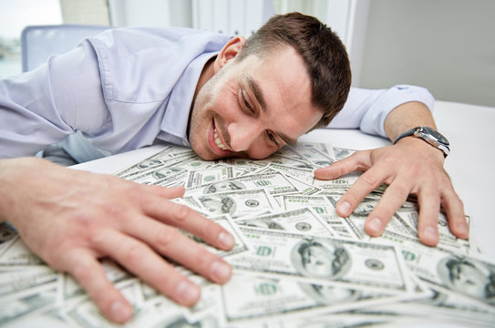 happy businessman with heap of money in office