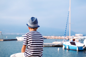 Fototapeta na wymiar child in hat looking at sea and ship