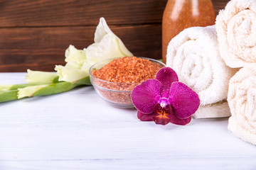 Close view at spa set: sea salt and orchid with towels and scrub on a background on white wooden table.  Central focus.