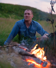 man sitting  near bonfire