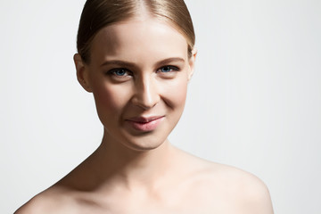 Young woman with perfect skin and blonde hair smiling at the camera