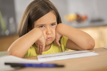 Portrait of little girl doing homework ar table