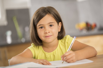 Portrait of little girl doing homework ar table