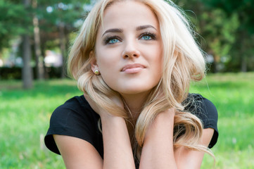 Young blond woman looking up sitting in the park