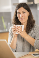 young woman working at home on laptop in kitchen