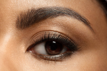 Close-up of make-up eye with long eyelashes and brown eyebrows of black woman