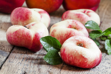Flat Nectarines with leaves on the old wooden table, selective f