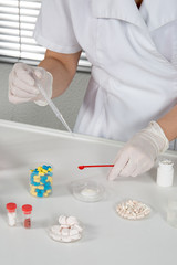 Chemical laboratory scene: woman scientist observing the indicator color of a pill