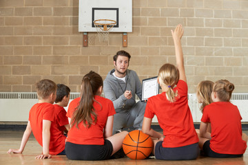 Coach Giving Team Talk To Elementary School Basketball Team