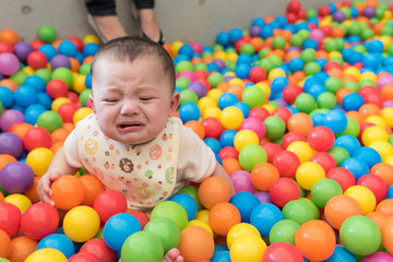 Fototapeta na wymiar Crying Baby Girl in Ball Pit