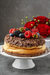 Cheesecake with chocolate topping decorated with summer fruits