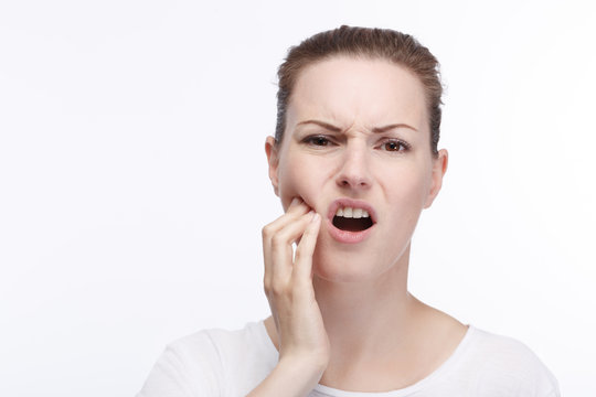 Junge hübsche Frau hält sich die Wange vor Zahnschmerzen