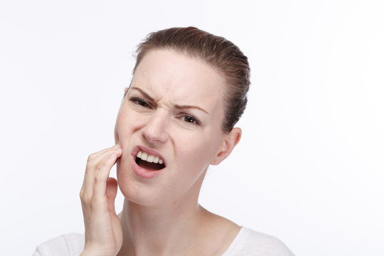 Junge hübsche Frau hält sich die Wange vor Zahnschmerzen