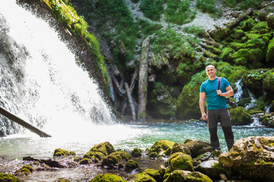 Tourist with camera near waterfall
