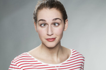 humor concept - portrait of a crosseyed young woman wearing a striped sweater having fun in practicing a funny face with her eyes
