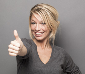 agreement concept - excited young woman with trendy blonde hair giving a thumb up for satisfaction