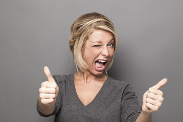 satisfaction concept - excited young blonde woman giving a double thumb up for agreement