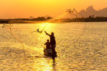 A fisherman throw a net to catch a fish in a river