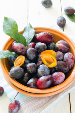 Plum in a ceramic bowl on a white wooden table