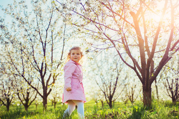 Child running outdoors blossom trees. Colorful toning effect.