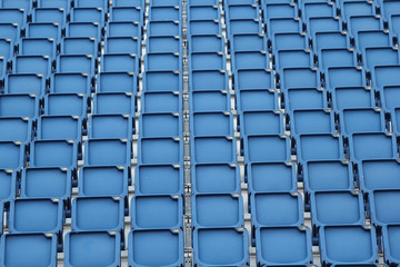 Fototapeta premium Plastikowe niebieskie siedzenia na tle stadionu piłkarskiego