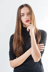Fashion model with long hair in black sweater poses on white