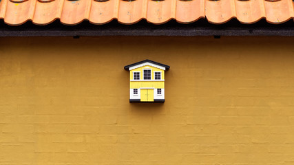 small yellow and whtite birdhouse on a "curry" yellow wall