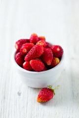 wild strawberries in a bowl on wooden surface