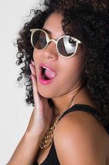 Headshot hispanic model wearing black sexy dress, golden necklace, sunglasses and curly wild hair posing sensually from profile angle