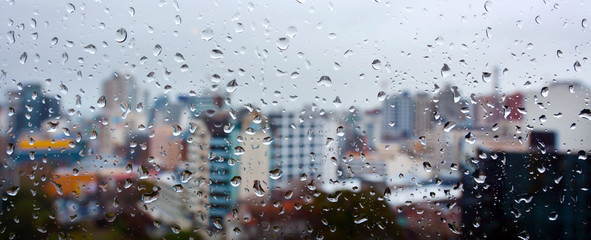 Panoramic urban view of rain drops falls on a window