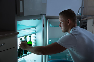 Man Removing Beer Bottle From Refrigerator