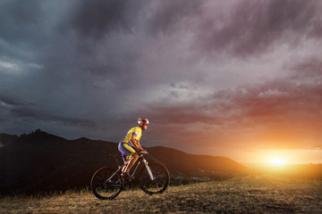 Fototapeta na wymiar mountain bike cyclist riding track on grass rocky trail above su