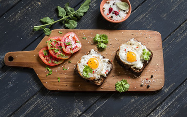 toast with feta cheese and fried quail egg, fresh tomatoes on a dark wooden surface - a healthy Breakfast or snack