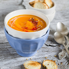 pumpkin soup in ceramic bowls on a light wooden background