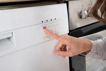 Person Hands On Button Of Dishwasher