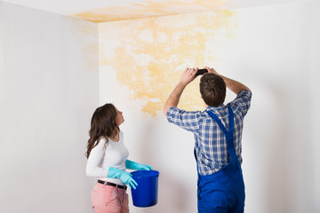 Handyman With Woman Photographing Ceiling At Home