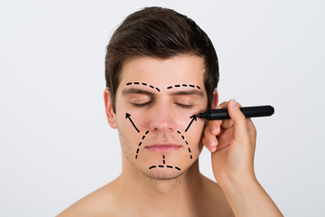 Person Hands Making Lines On Face Of Man