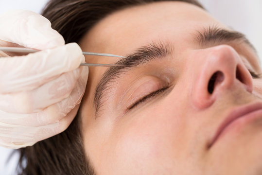 Beautician Hands Plucking Man Eyebrows With Tweezers