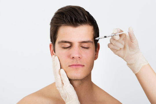 Hands Injecting Syringe Into Man's Face