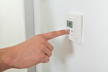 Person Hands Adjusting Temperature On A Digital Thermostat