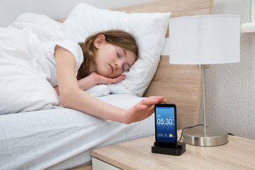 Girl On Bed Snoozing Mobile Phone Alarm