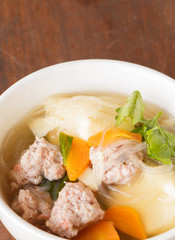 clear soup with pork in white plate put on wooden background, Thai cuisine.