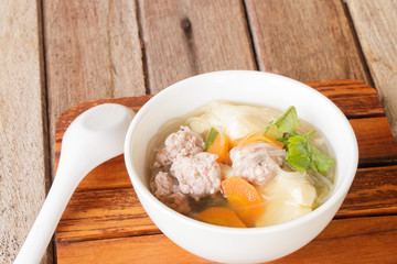 clear soup with pork in white plate put on wooden background, Thai cuisine.