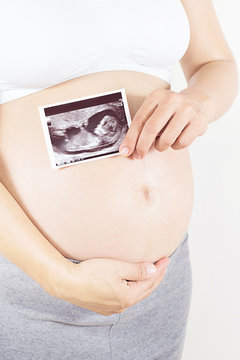 pregnant woman holding the digital echography photograph of her