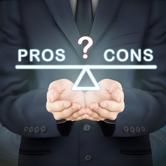 businessman holding pros and cons seesaw